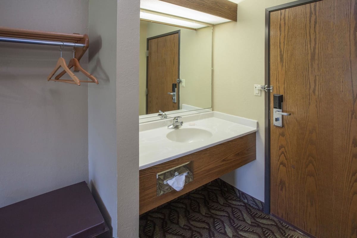 Une salle de bain avec un meuble-lavabo en bois, un évier, un miroir et une porte.