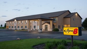 A Super 8 hotel with a large parking lot and a well-maintained lawn.