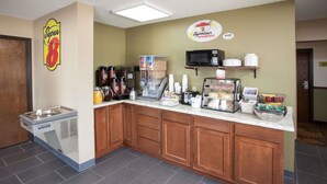 A breakfast bar with coffee machines, a microwave, and a beverage dispenser.