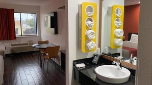A hotel room with a dining area, a large window with curtains, a round table, and a modern bathroom with a sink and mirror. - Relax Inn (Franklin)