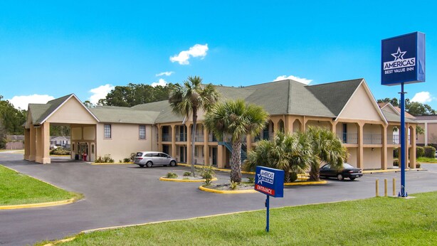 A motel with a central entrance, multiple parking spaces, and a clear sky. - Americas Best Value Inn Darien (Darien)