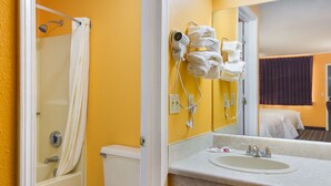 A bathroom with a bathtub, toilet, and sink. There are towels and a hairdryer on the wall.