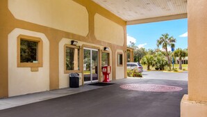 A building with a covered entrance, a trash bin, and a red fire hydrant. - Americas Best Value Inn Darien (Darien)