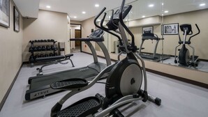 A gym with treadmills, an elliptical, and a bench. There are dumbbells on a rack and a mirror reflecting the equipment. - Sleep Inn Madison (Madison)