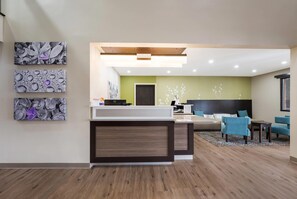 A modern hotel lobby with a reception desk, seating area, and artwork on the walls.