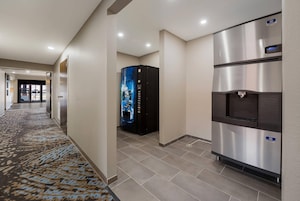 Un pasillo de hotel con dispensador de agua y un refrigerador de acero inoxidable.