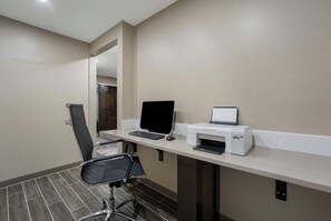 Un espace de bureau moderne comprenant un bureau, un ordinateur portable, une imprimante et un fauteuil de bureau noir.