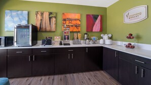 A modern kitchen with dark cabinets, a refrigerator, coffee machine, and a breakfast bar. - Sleep Inn Madison (Madison)