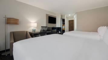 Habitación de hotel con dos camas, un escritorio, una silla, un televisor y un armario.