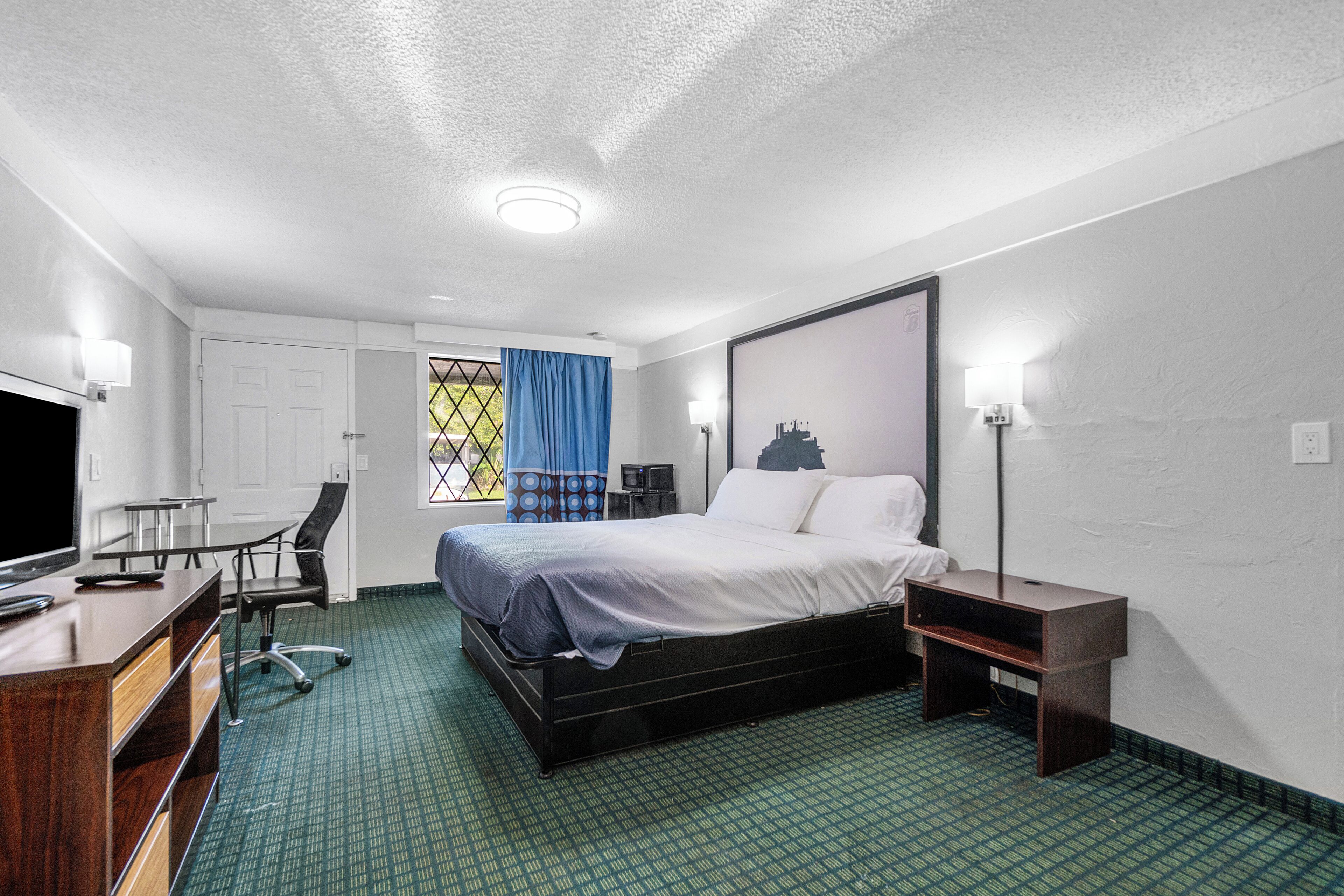 Une chambre d’hôtel équipée d’un lit, d’un bureau, d’une chaise et d’un téléviseur.