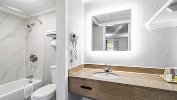 A modern bathroom with a marble shower, a toilet, and a sink with a mirror above it.