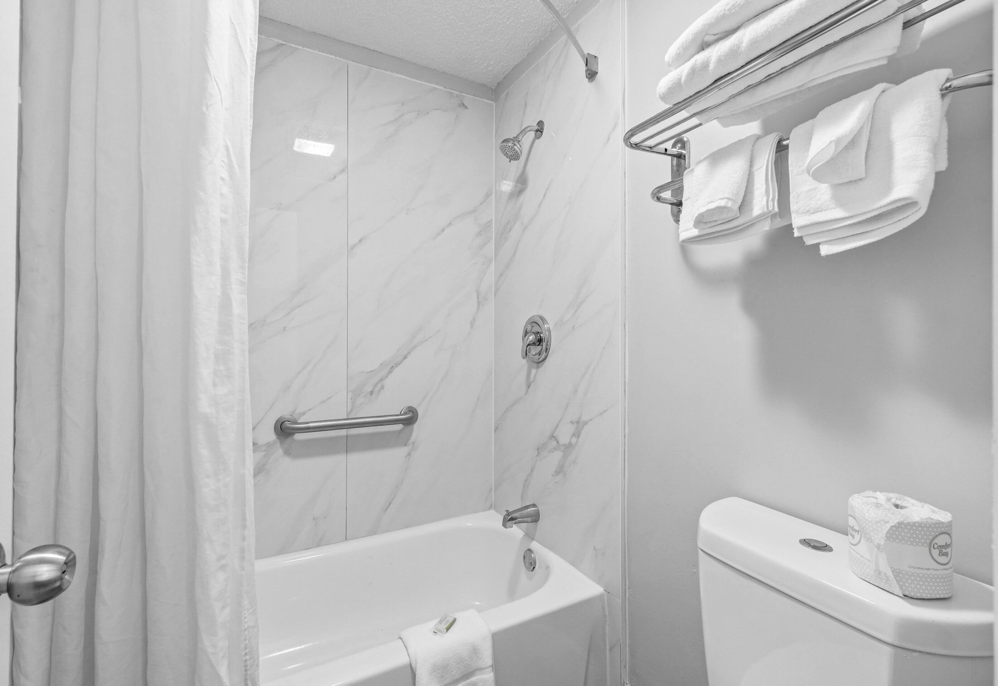 Un baño con bañera, ducha e inodoro. Toallas colgadas en un tendedero.