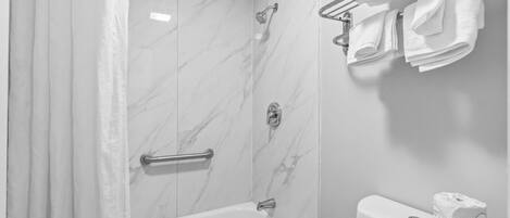 Un baño con bañera, ducha e inodoro. Toallas colgadas en un tendedero.