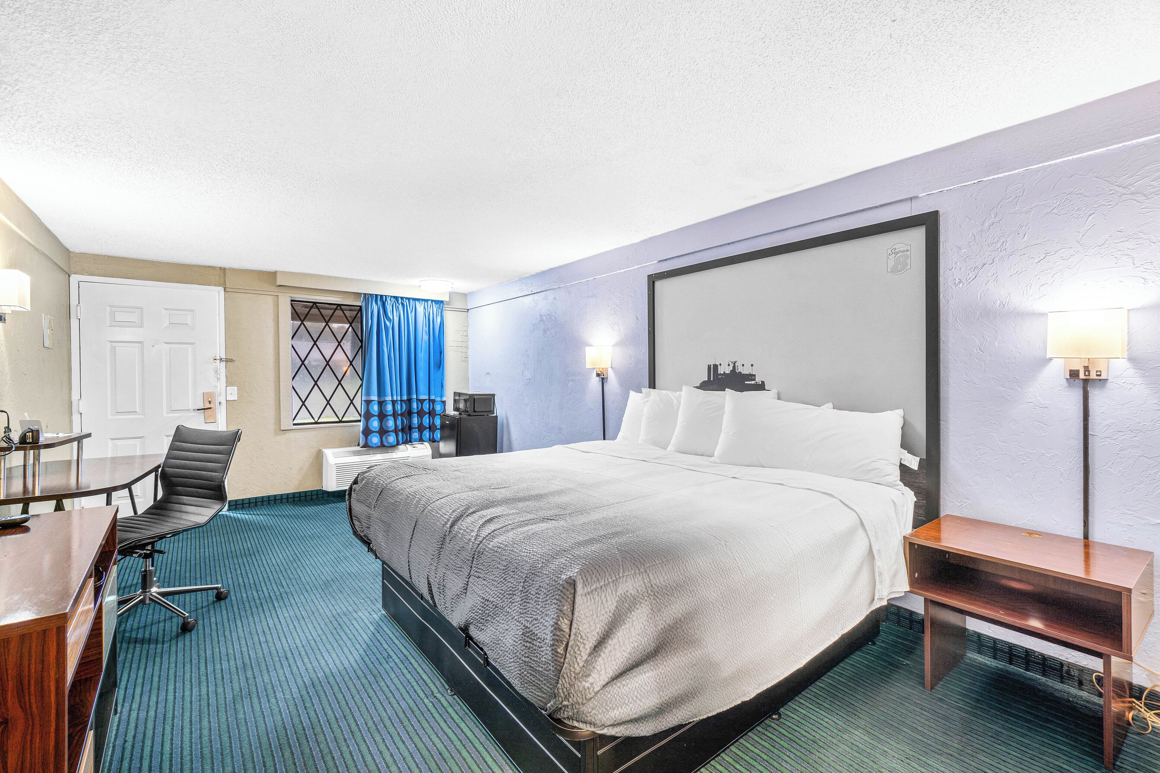 Une chambre d’hôtel avec un lit, un bureau, une chaise et une petite table.