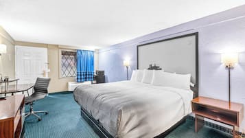 Une chambre d’hôtel avec un lit, un bureau, une chaise et une petite table.