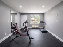 Un gimnasio en casa con equipo de ejercicio, una cinta de correr y un espejo grande.