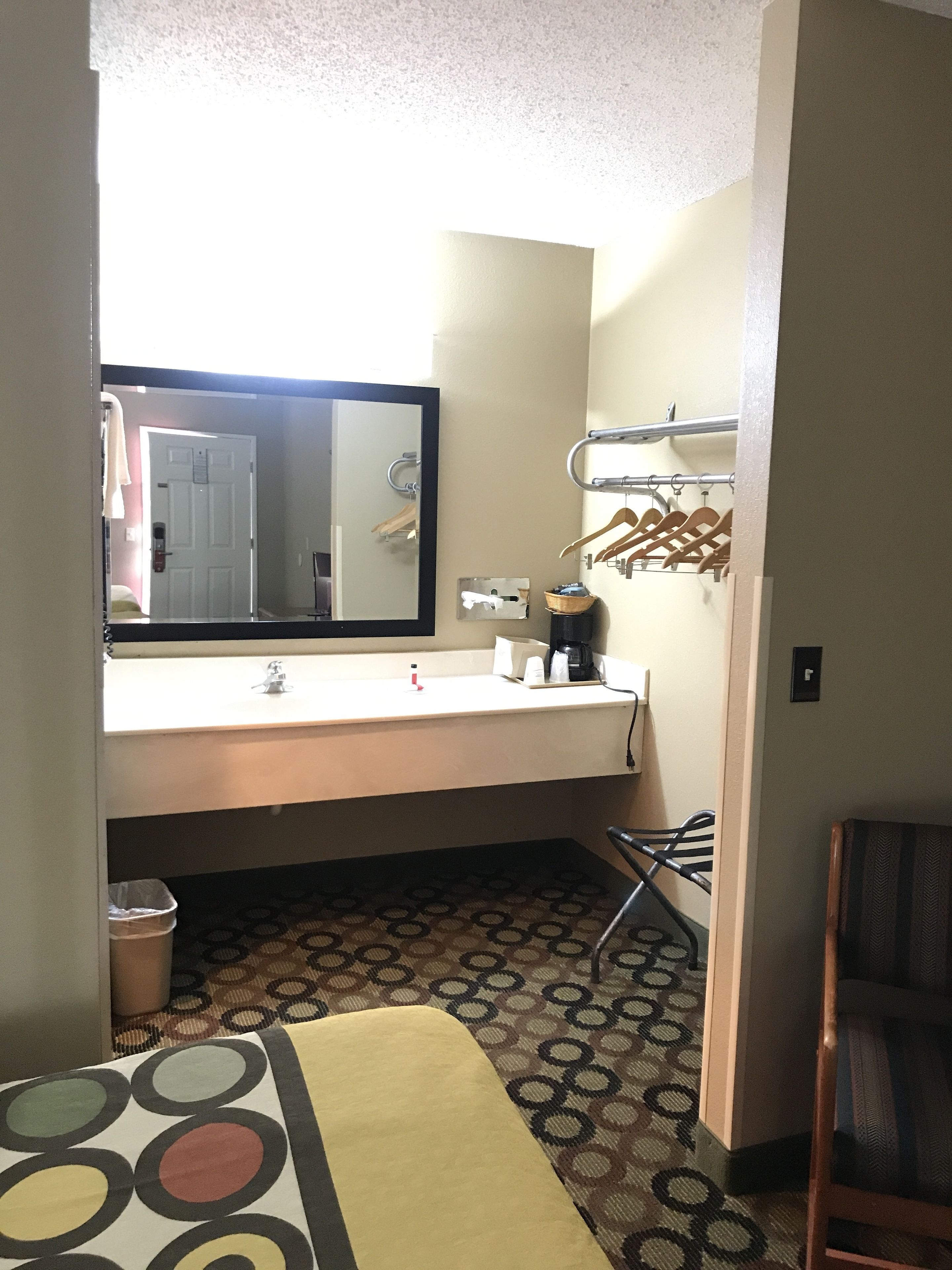 Un baño de hotel pequeño con lavamanos, espejo, toallero y piso con diseño.