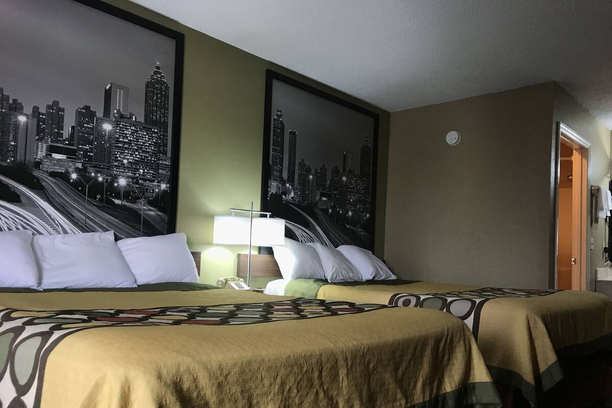 Quarto de hotel com duas camas, vista para a cidade, telefone e mesa de cabeceira.