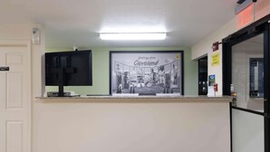 A reception desk with a framed welcome sign, a flat-screen TV, and a water dispenser. - Super 8 by Wyndham Cleveland (Cleveland)