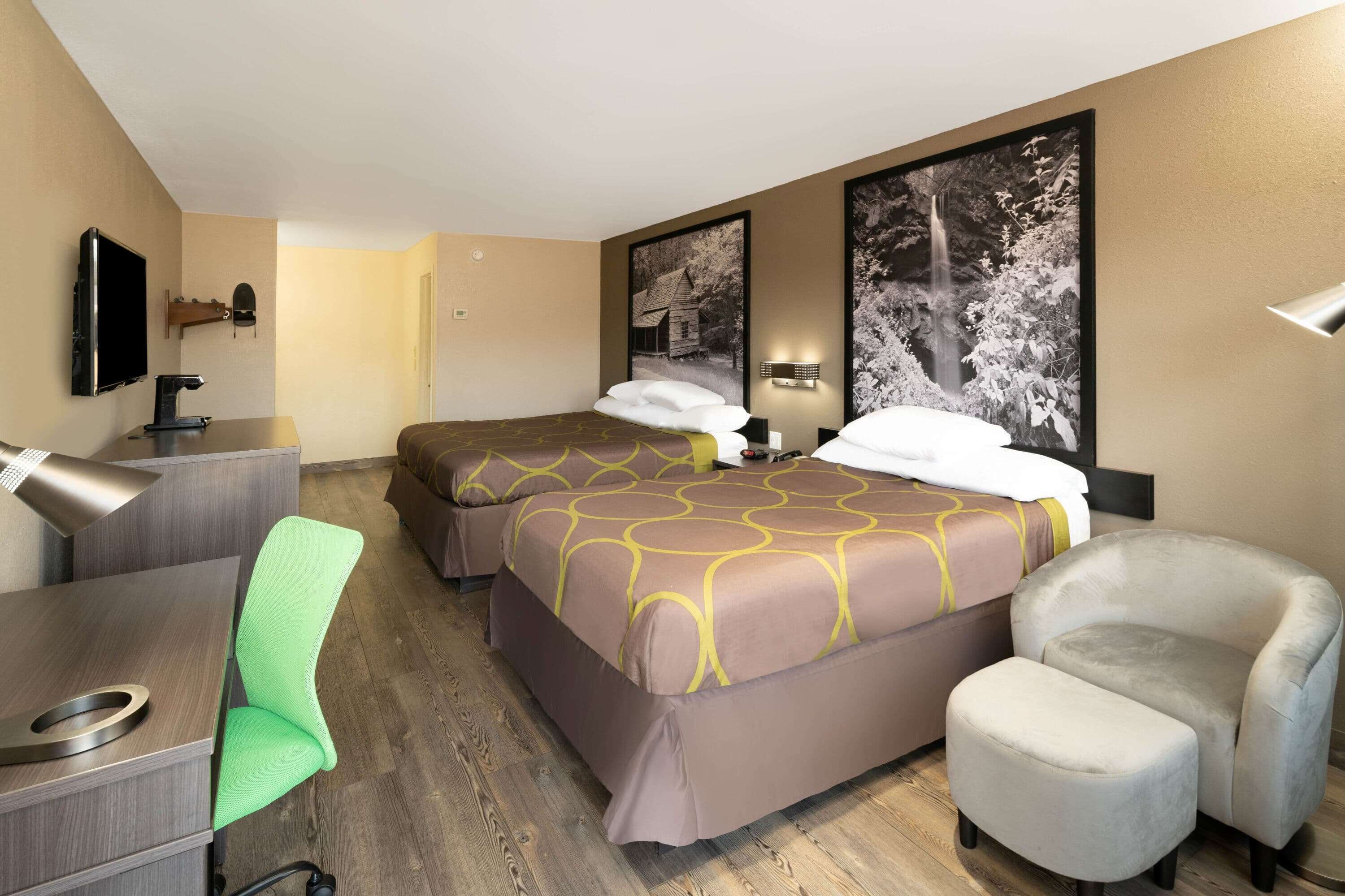 A hotel room with two beds, a desk, a chair, and a sofa.
