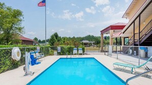 A swimming pool with a flag, lounge chairs, and a covered area. - Super 8 by Wyndham Cleveland (Cleveland)