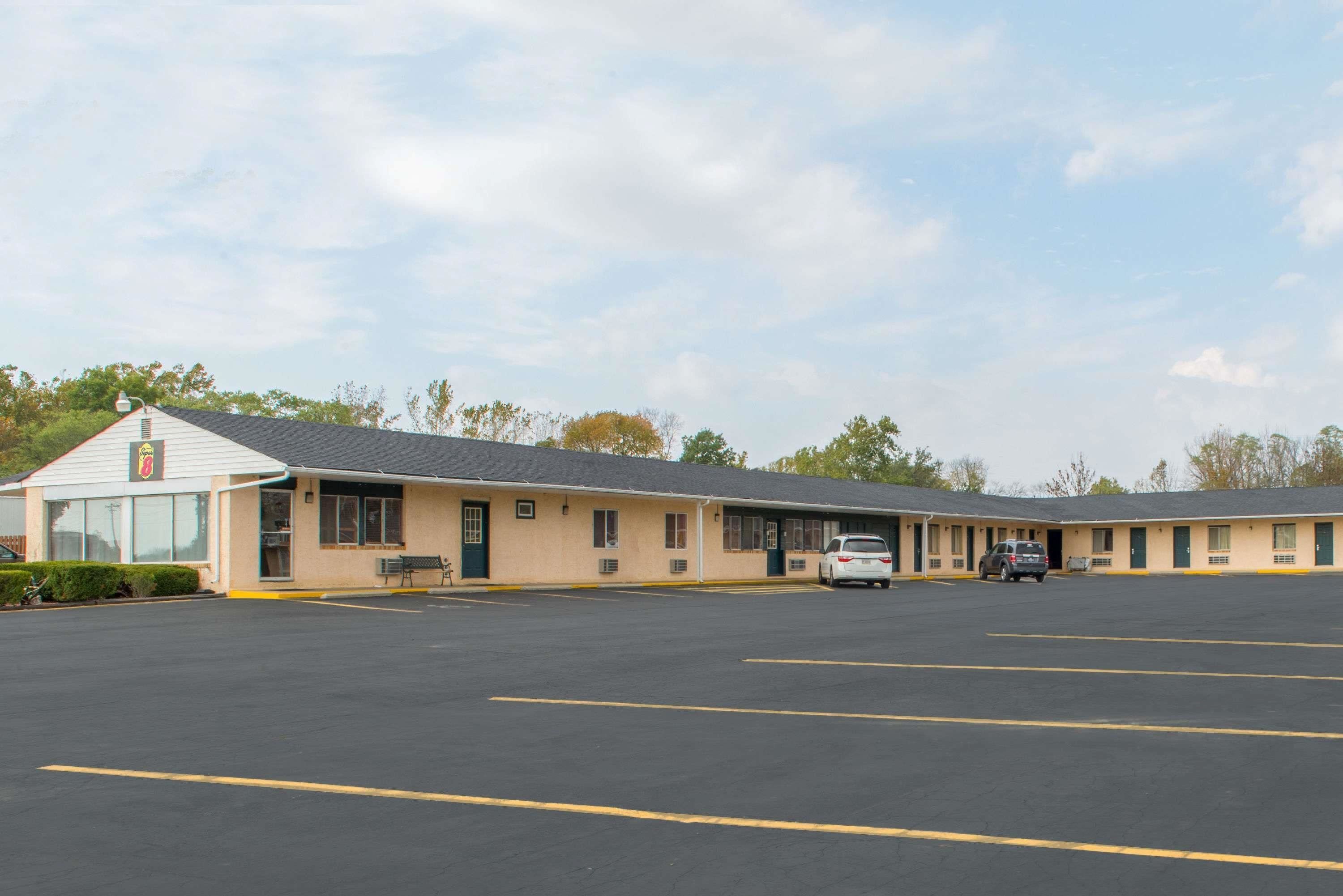 A motel with a parking lot, a single-story building, and a small outdoor seating area.