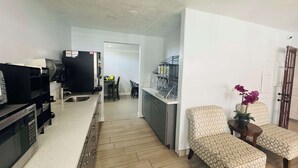 A modern kitchen with a built-in oven and microwave, a dining area with a table and chairs, and a small seating area with patterned cushions. - SureStay by Best Western Fresno Central (Fresno)