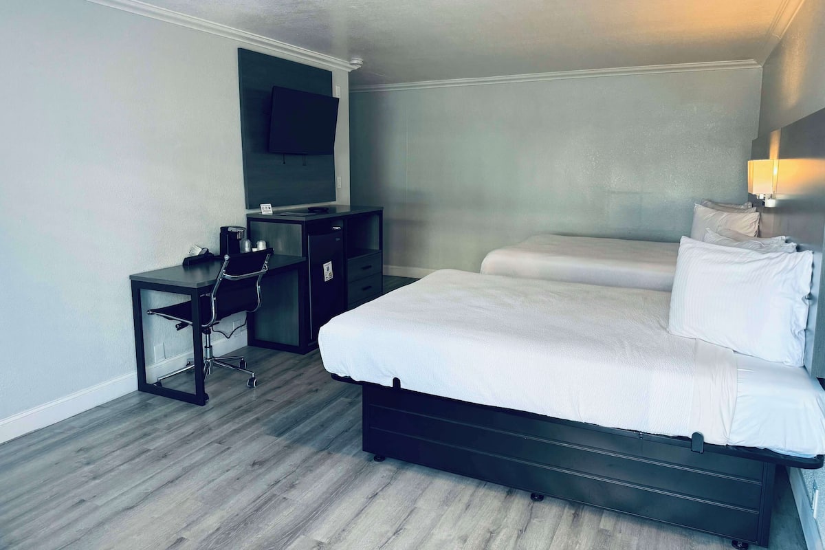 Une chambre d’hôtel équipée d’un lit, d’un bureau, d’une chaise, d’une télévision et d’une lampe de chevet.
