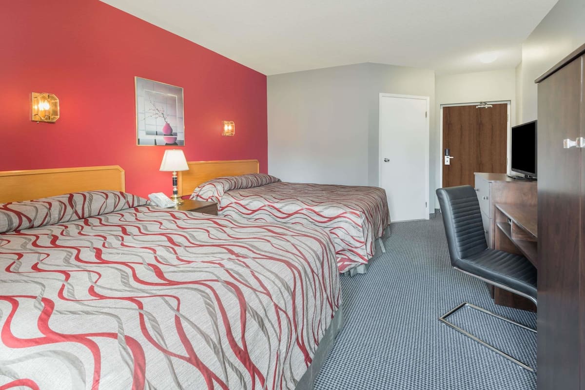 A hotel room with a bed, a desk, a TV, and a door.