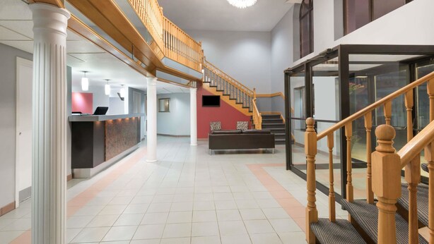 A spacious lobby with a staircase, a reception desk, and a bench.