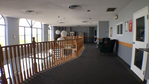 A hotel corridor with a wooden railing, a staircase, and a seating area with chairs.