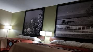 A hotel room with a bed, two lamps, and two large framed pictures on the wall.
