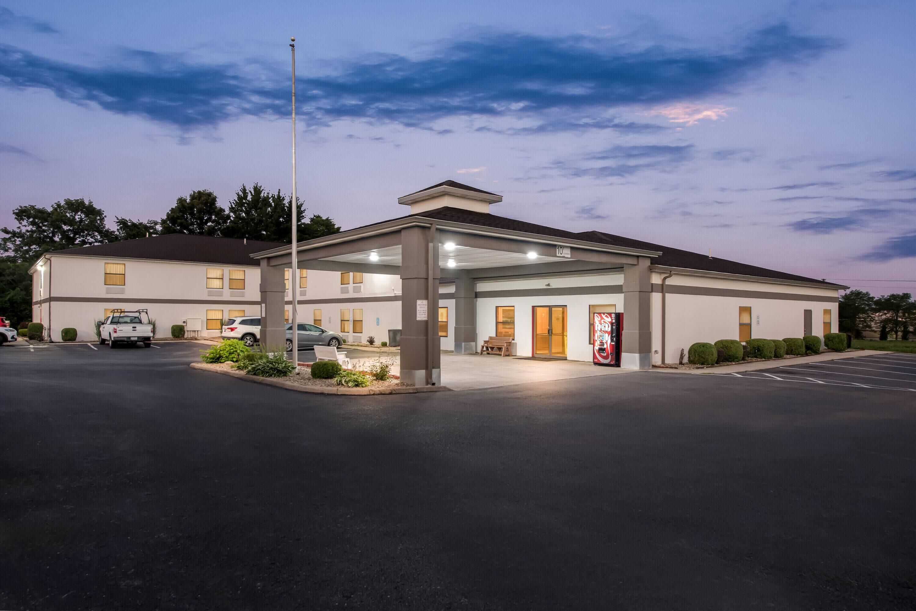 A building with a covered entrance, a parking lot, and a flag outside.