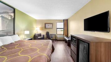 A hotel room with a bed, desk, chair, television, and a window with curtains.