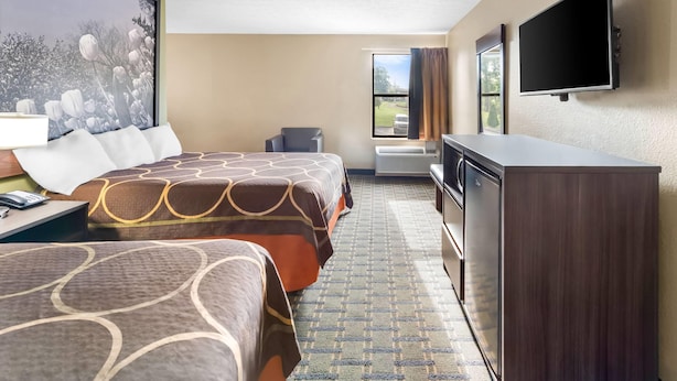 Habitación de hotel con dos camas, un televisor de pantalla plana, un escritorio con lámpara, cómoda y un ventanal con vistas al exterior.