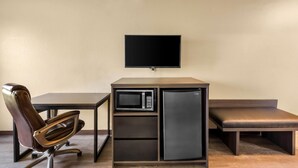 Una kitchenette compacta con microondas, refrigerador y un televisor de pantalla plana.