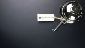 Een sleutel met een label waarop 'Magnuson Hotels' staat, bevestigd aan een deurklink.