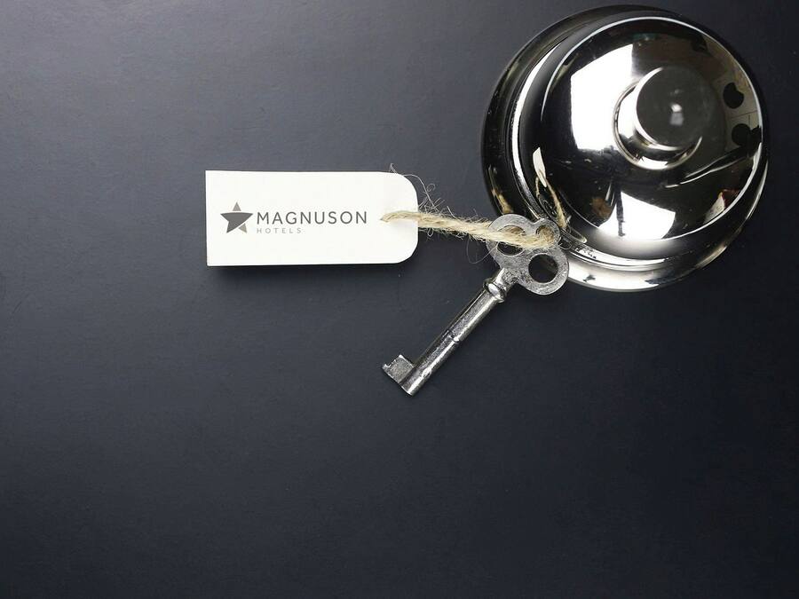 Uma chave com uma etiqueta identificando 'Magnuson Hotels' presa ao puxador da porta.