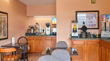 A small, cozy cafe with a wooden counter, a coffee machine, and a few chairs.