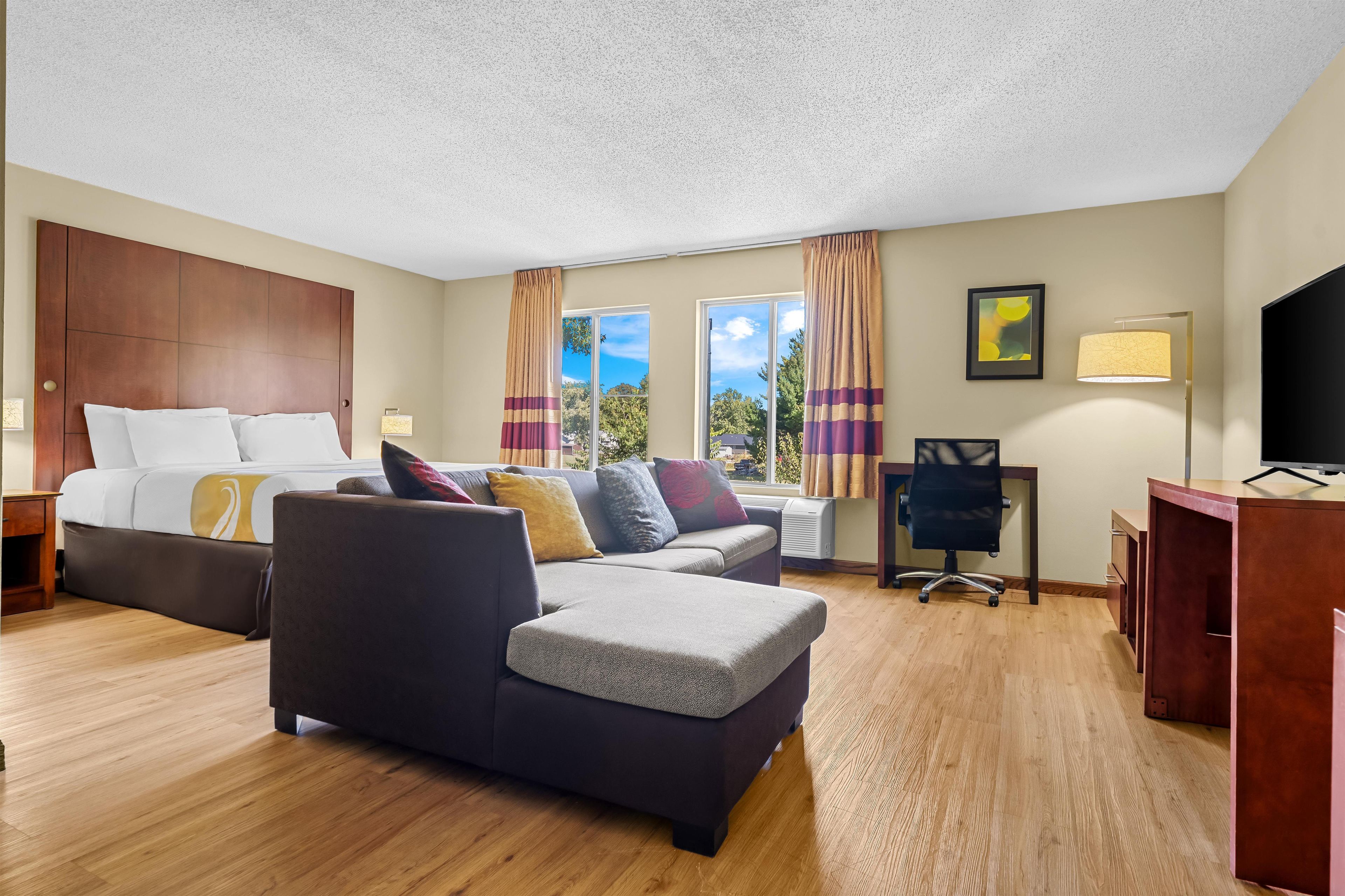 A hotel room with a bed, a sofa, a desk, and a television.
