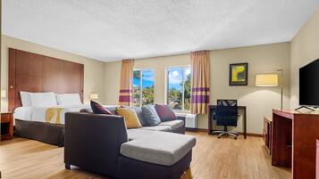 A hotel room with a bed, a sofa, a desk, and a television.