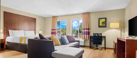 A hotel room with a bed, a sofa, a desk, and a television.