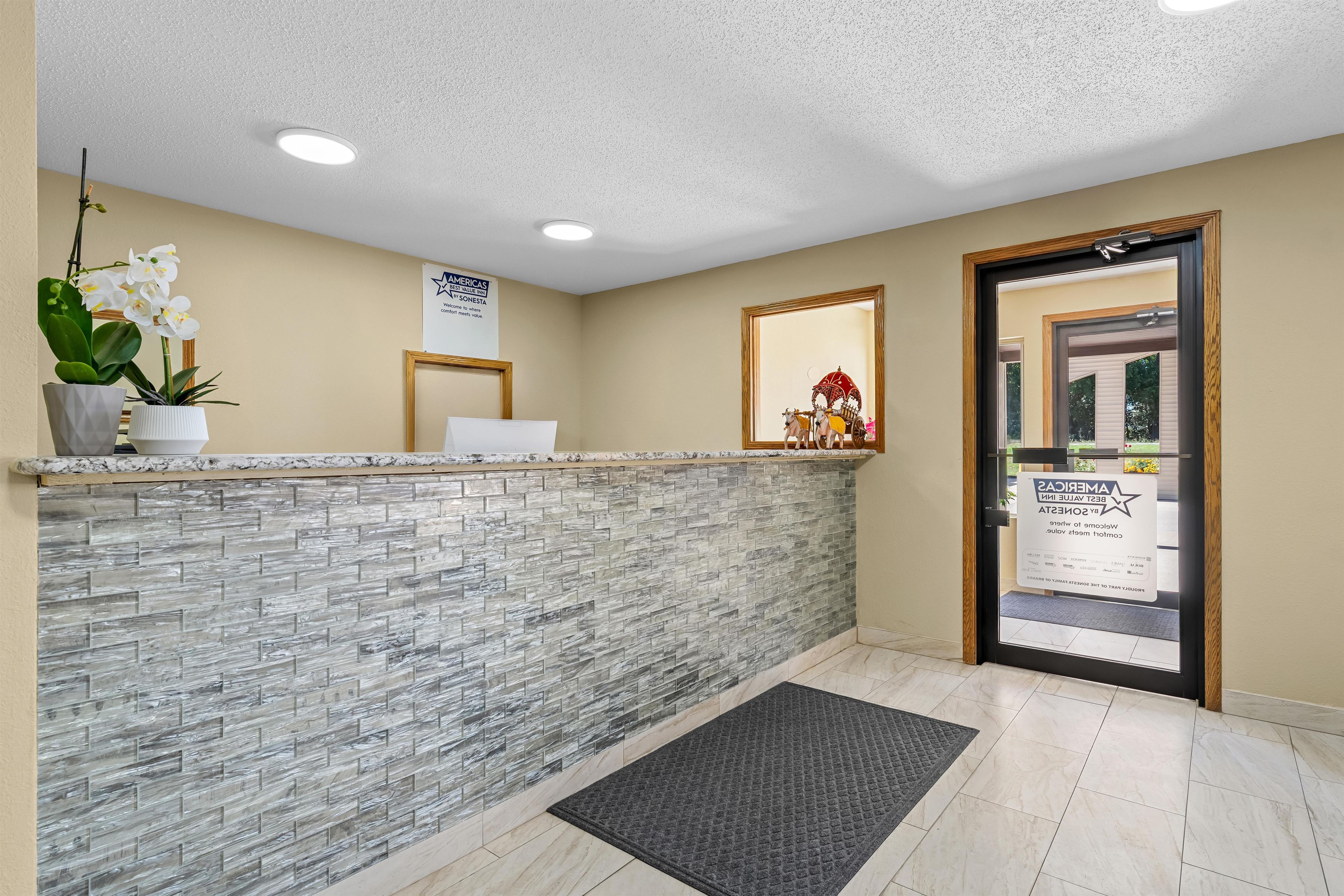 A reception area with a stone-textured counter, a potted orchid, and a framed welcome sign.