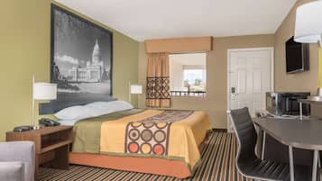 A hotel room with a bed, a desk, a chair, a TV, and a large window.