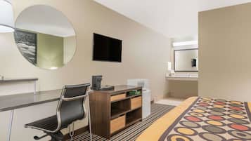 A hotel room with a desk, chair, bed, and a large mirror.