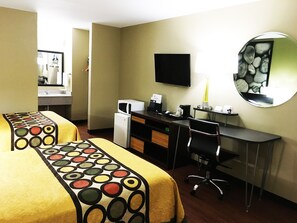 Habitación de hotel con dos camas, un escritorio, una silla, un televisor de pantalla plana, microondas, refrigerador y espejo.