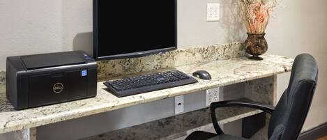 Un espacio de trabajo en casa con una computadora de escritorio, monitor, teclado, ratón e impresora sobre una encimera de mármol.