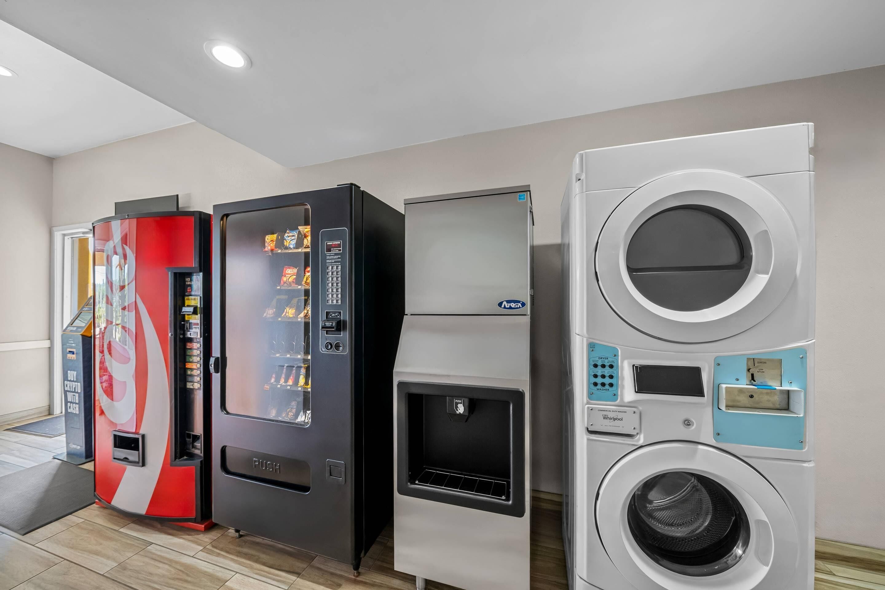 Un espacio comercial con máquinas expendedoras, un refrigerador y una lavadora grande.