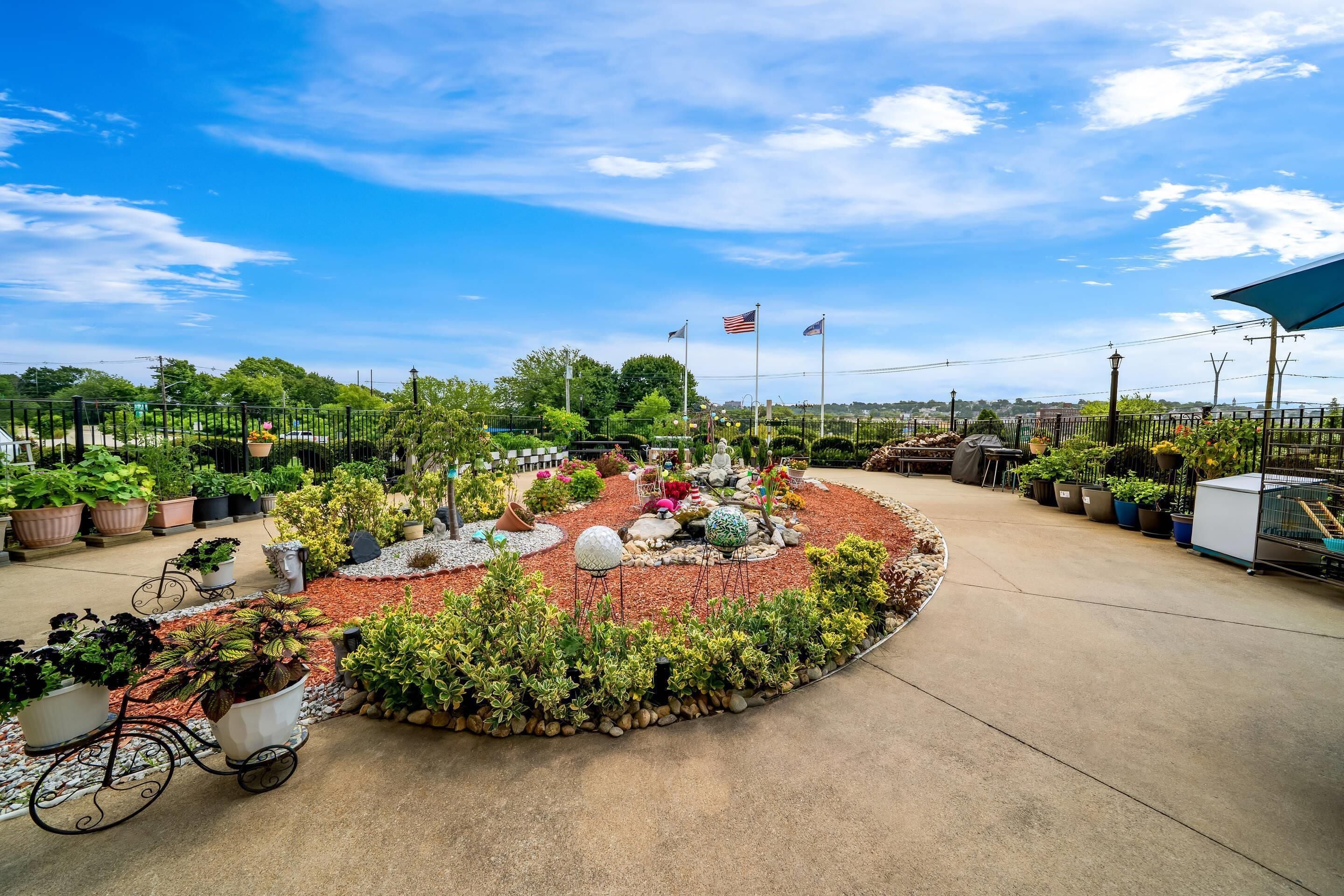 A garden with a circular stone path, potted plants, and a statue.