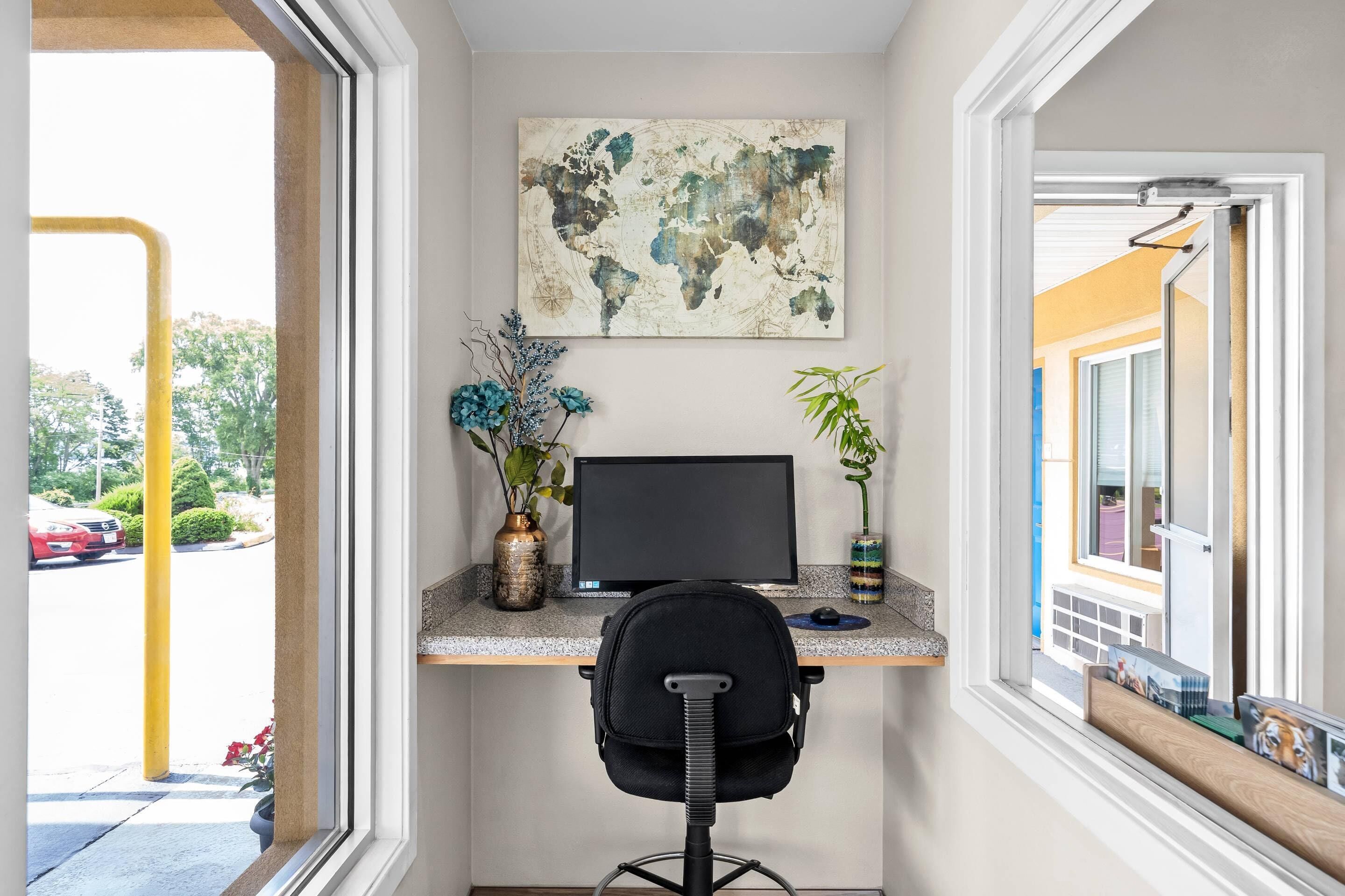A home office with a desk, computer, chair, and decorative plants.
